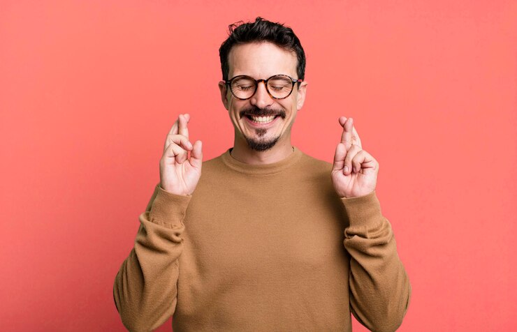 Foto sorrindo e cruzando ansiosamente os dois dedos sentindo-se preocupado e desejando ou esperando boa sorte
