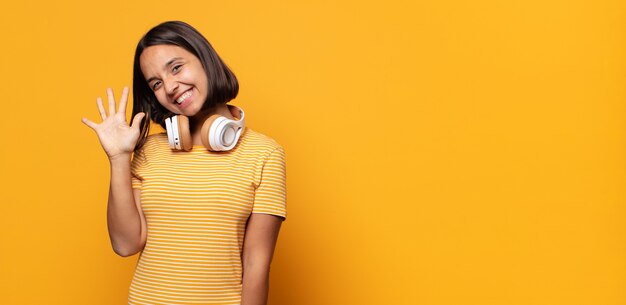 sorrindo e parecendo amigável, mostrando o número cinco ou quinto com a mão para a frente, em contagem regressiva