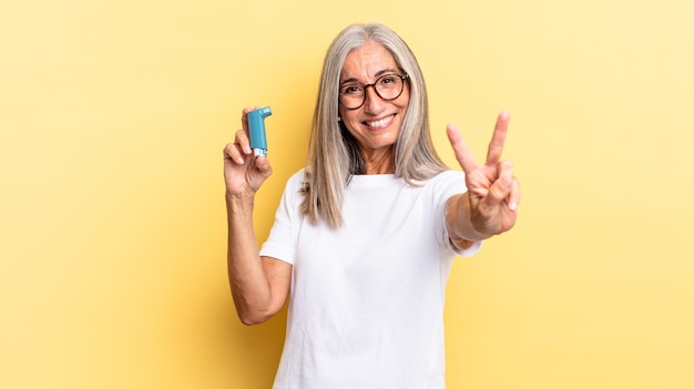 Sorrindo e parecendo amigável, mostrando o número dois ou o segundo com a mão para a frente, em contagem regressiva. conceito de asma