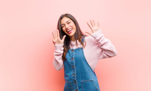 sorrindo e parecendo amigável, mostrando o número nove ou nono com a mão para a frente, contando