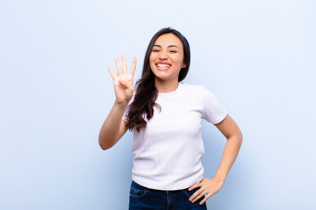 sorrindo e parecendo amigável, mostrando o número quatro ou quarto com a mão para a frente, contando