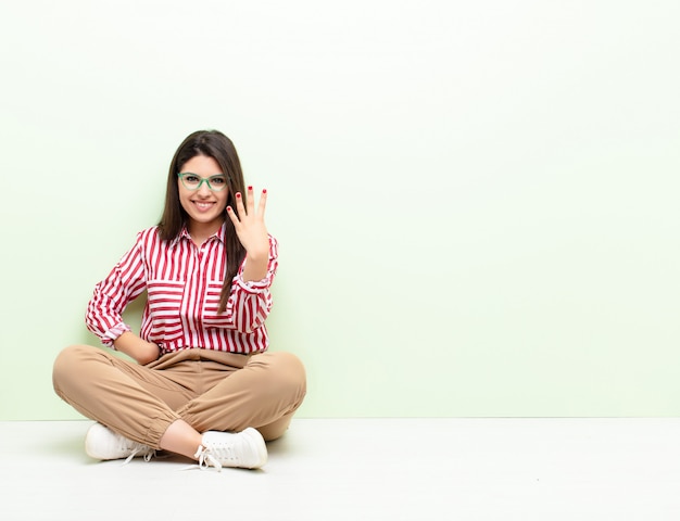 sorrindo e parecendo amigável, mostrando o número quatro ou quarto com a mão para a frente, contando