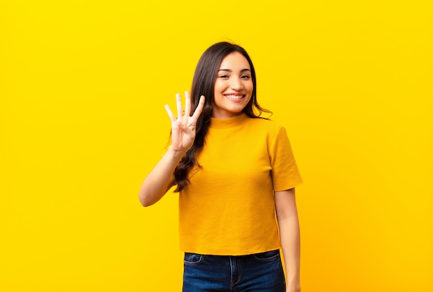 sorrindo e parecendo amigável, mostrando o número quatro ou quarto com a mão para a frente, contando