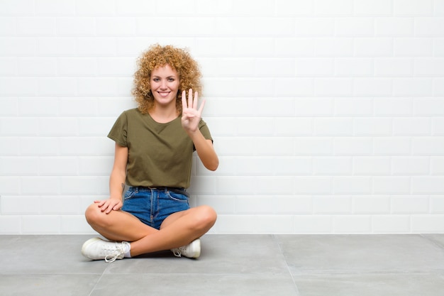 sorrindo e parecendo amigável, mostrando o número quatro ou quarto com a mão para a frente, contando