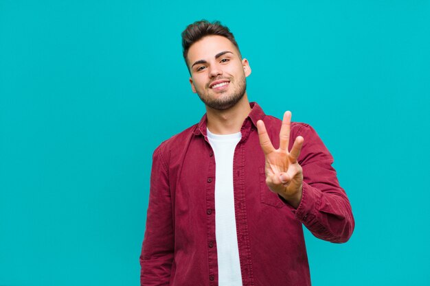 sorrindo e parecendo amigável, mostrando o número três ou o terceiro com a mão para a frente, contando