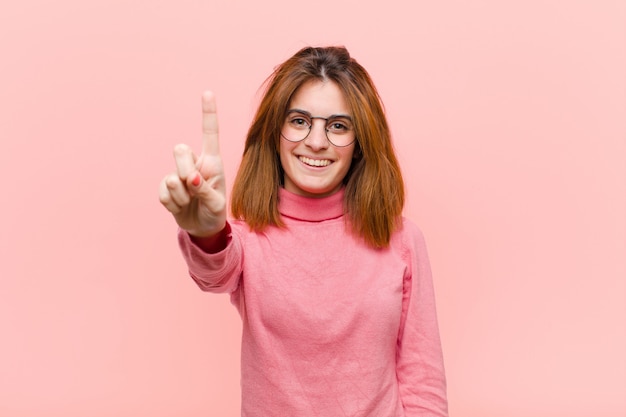 sorrindo e parecendo amigável, mostrando o número um ou o primeiro com a mão para a frente, contando