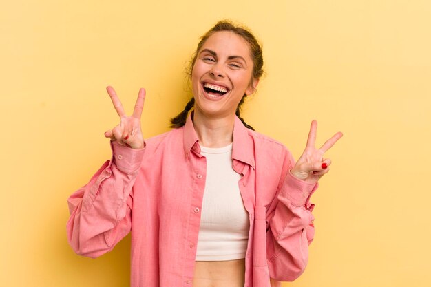 Sorrindo e parecendo feliz, amigável e satisfeito, gesticulando vitória ou paz com as duas mãos