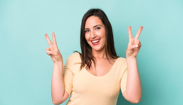 Sorrindo e parecendo feliz, amigável e satisfeito, gesticulando vitória ou paz com as duas mãos