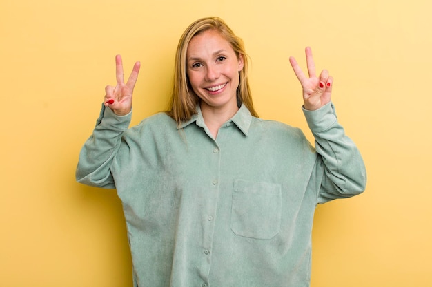 Sorrindo e parecendo feliz, amigável e satisfeito, gesticulando vitória ou paz com as duas mãos