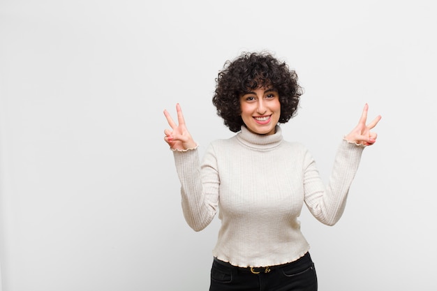 sorrindo e parecendo feliz, amigável e satisfeito, gesticulando vitória ou paz com as duas mãos