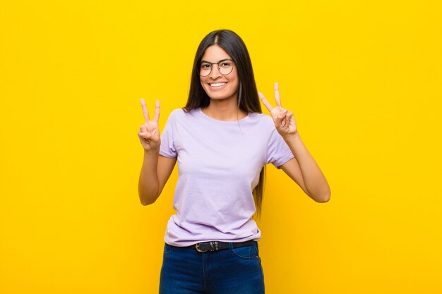 sorrindo e parecendo feliz, amigável e satisfeito, gesticulando vitória ou paz com as duas mãos