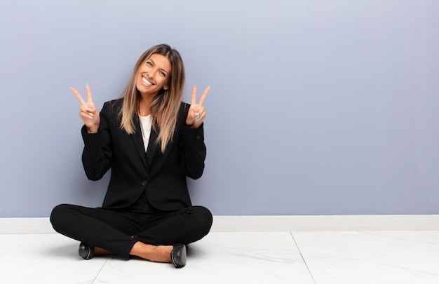 sorrindo e parecendo feliz, amigável e satisfeito, gesticulando vitória ou paz com as duas mãos