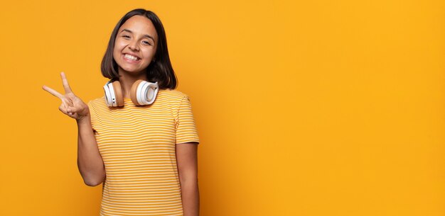 sorrindo e parecendo feliz, despreocupado e positivo, gesticulando vitória ou paz com uma mão