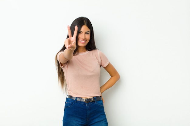 sorrindo e parecendo feliz, despreocupado e positivo, gesticulando vitória ou paz com uma mão