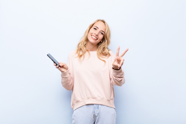 sorrindo e parecendo feliz, despreocupado e positivo, gesticulando vitória ou paz com uma mão