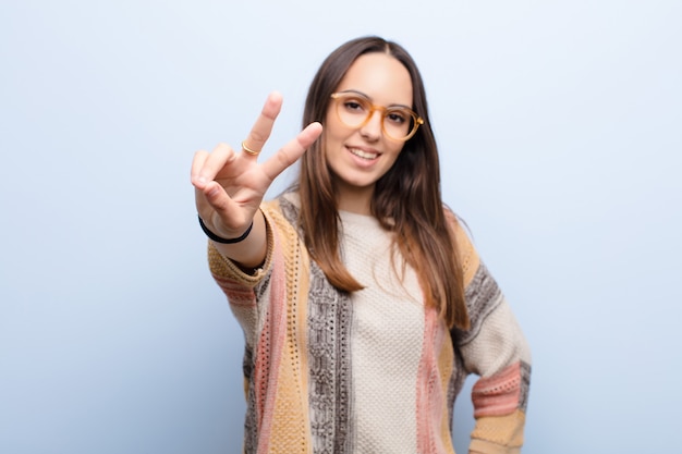 sorrindo e parecendo feliz, despreocupado e positivo, gesticulando vitória ou paz com uma mão