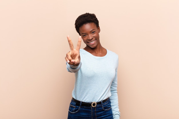 sorrindo e parecendo feliz, despreocupado e positivo, gesticulando vitória ou paz com uma mão