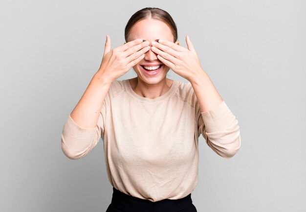 Sorrindo e sentindo-se feliz cobrindo os olhos com as duas mãos e esperando uma surpresa inacreditável