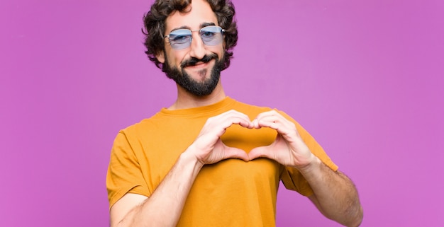 sorrindo e sentindo-se feliz, fofo, romântico e apaixonado, fazendo formato de coração com as duas mãos