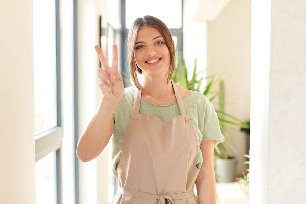 Sorrindo e uma mulher parecendo feliz, despreocupada e positiva, gesticulando vitória ou paz com uma mão