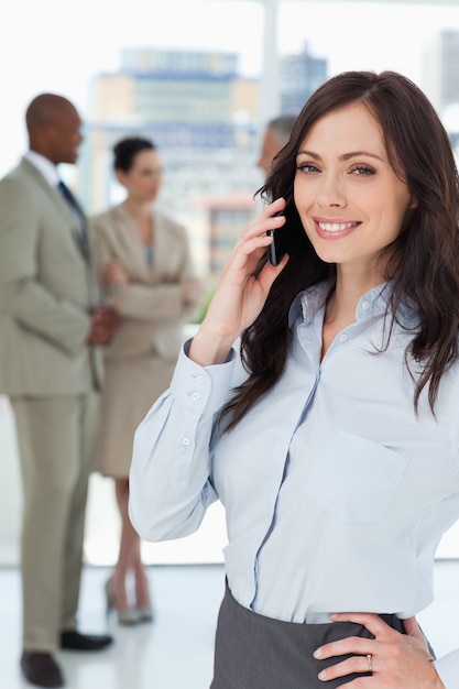 Sorrindo empresária falando ao telefone com uma mão no quadril