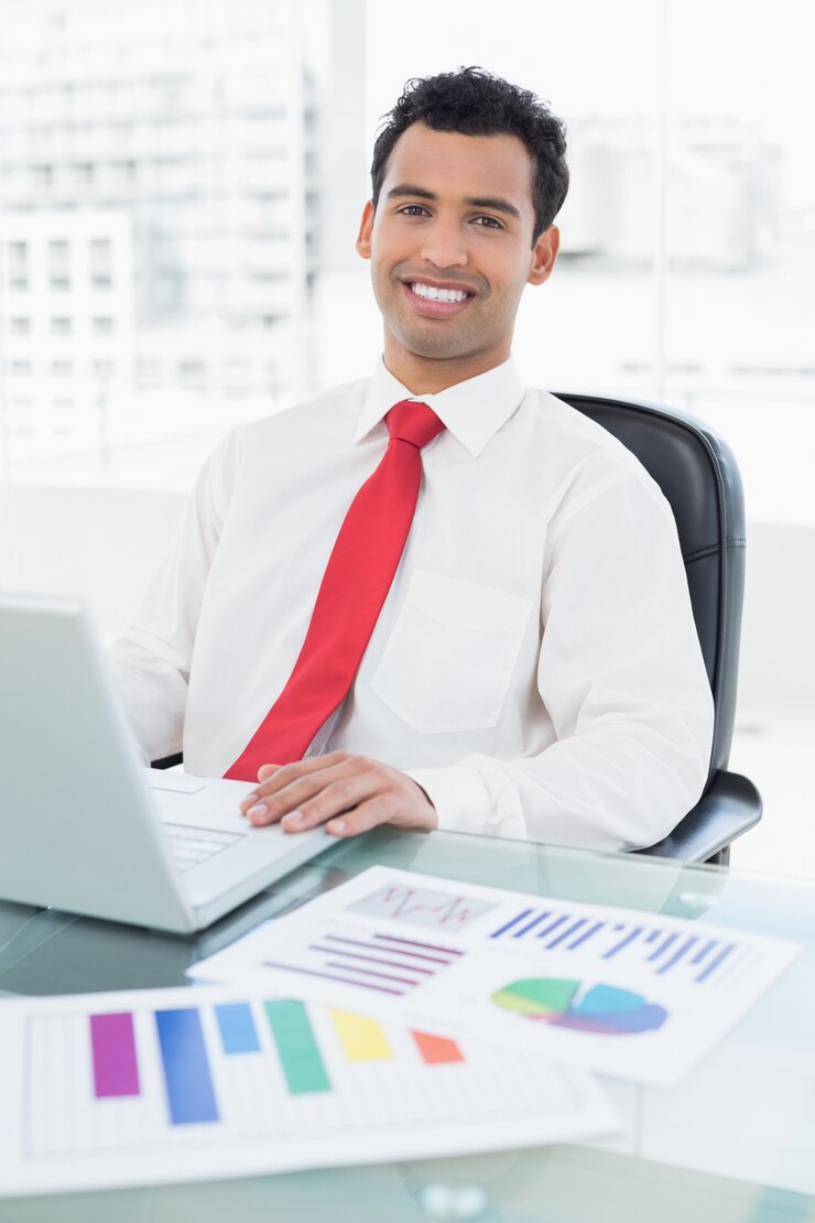 Foto sorrindo empresário com laptop e gráficos sentados no escritório