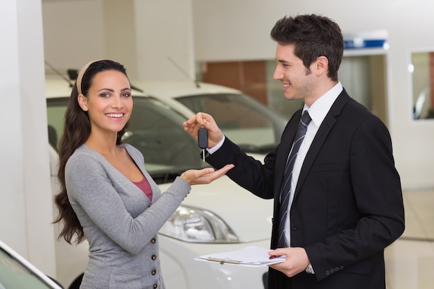 Sorrindo empresário dando chave do carro para o cliente feliz