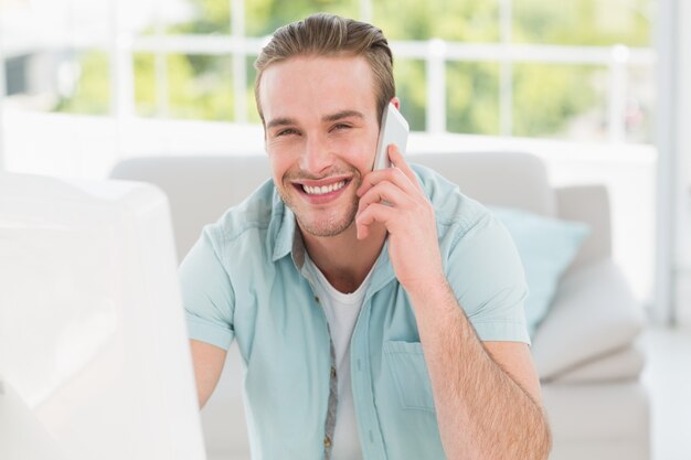 Sorrindo empresário no telefone enquanto usa o computador