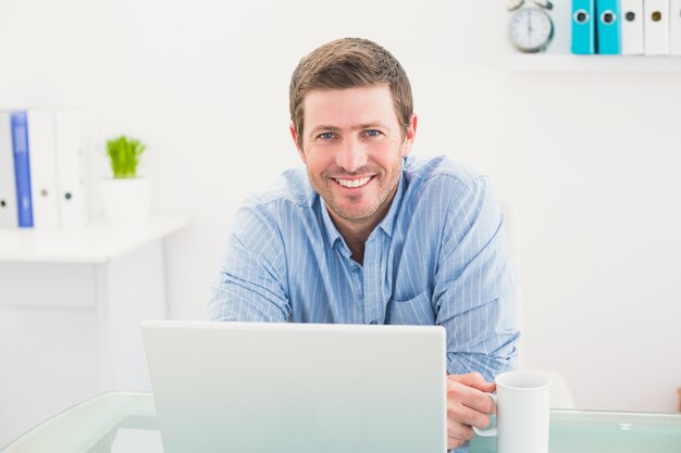 Sorrindo empresário segurando a caneca na mesa