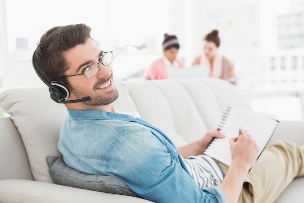 Sorrindo empresário telefonando e tomando notas no sofá