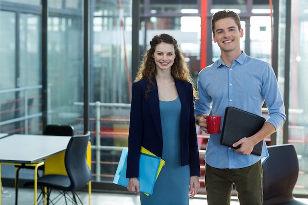 Foto sorrindo empresários de pé com arquivo e área de transferência no escritório