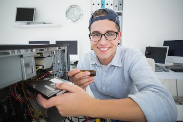 Sorrindo engenheiro de informática trabalhando no console quebrado com chave de fenda