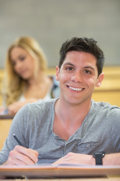 Sorrindo estudante do sexo masculino durante a aula na sala de aula