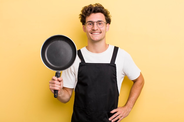 sorrindo feliz com uma mão no quadril e confiante