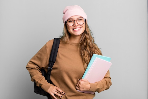 sorrindo feliz com uma mão no quadril e confiante