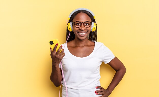 Sorrindo feliz com uma mão no quadril e uma atitude confiante, positiva, orgulhosa e amigável e ouvindo música