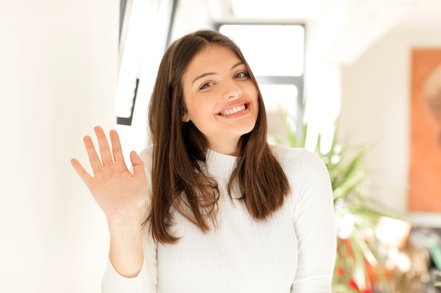 Sorrindo feliz e alegremente acenando com a mão e cumprimentando você ou dizendo adeus