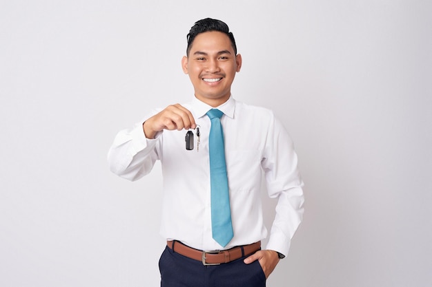 Sorrindo feliz jovem empresário asiático segurando a chave do carro na mão isolada no fundo branco realização carreira riqueza conceito de negócio