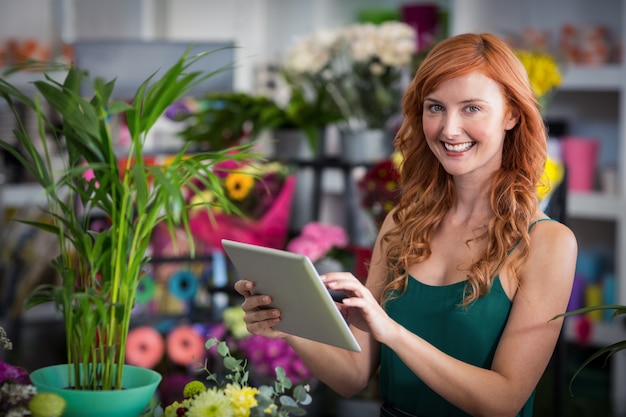 Sorrindo florista feminina usando tablet digital em floricultura