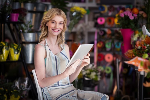 Sorrindo florista feminina usando tablet digital na loja de florista