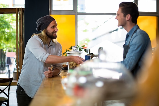 Sorrindo garçom servindo café para homem no balcão