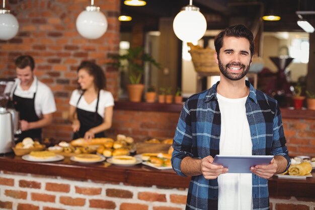 Foto sorrindo hipster usando tablet na frente do barista de trabalho