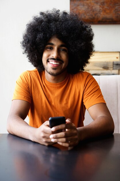 Sorrindo, homem americano africano, sentando, casa, com, telefone móvel