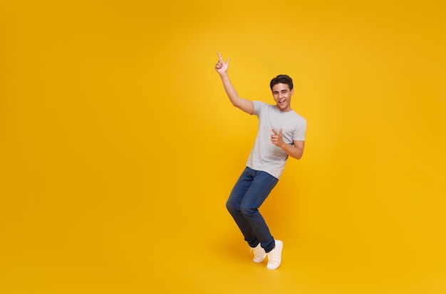 sorrindo homem asiático bonito apontando dedos para o espaço vazio de lado isolado em fundo amarelo