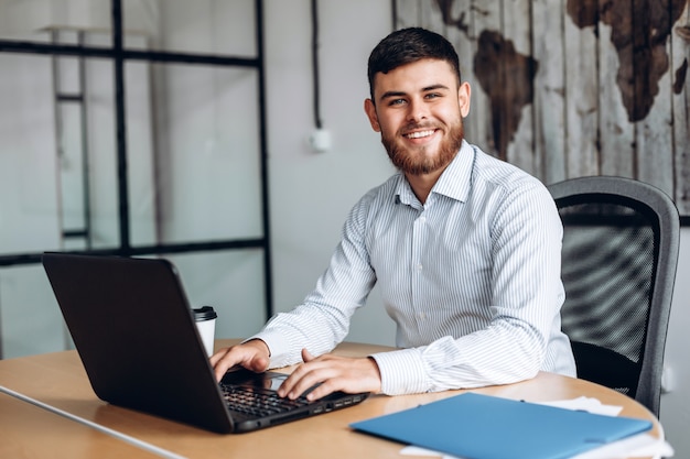 Sorrindo, homem barbudo trabalhando no computador no escritório