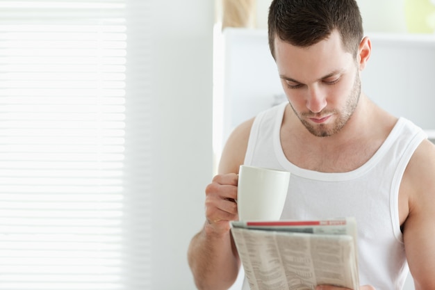Sorrindo homem bebendo café enquanto lê as notícias
