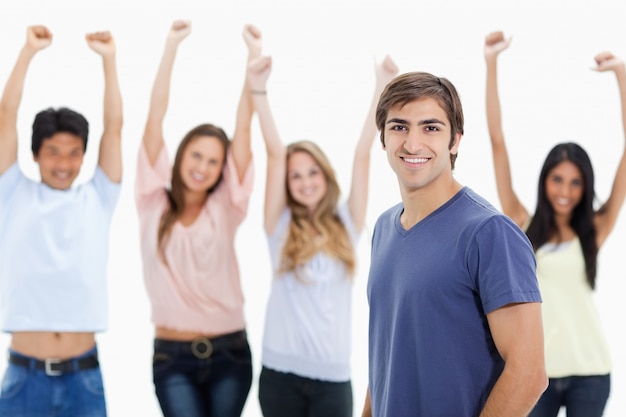 Sorrindo homem com pessoas atrás dele levantando os braços