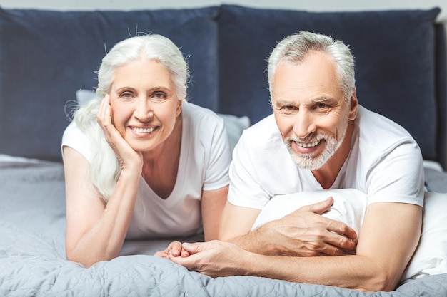 Sorrindo homem e mulher deitada na cama e olhando para a câmera