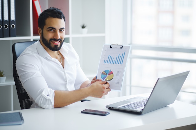 Sorrindo, homem negócios, usando computador portátil, escrivaninha, em, escritório