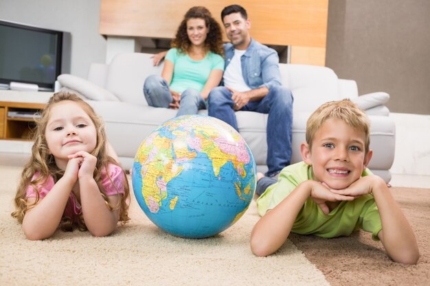 Sorrindo irmãos deitado no tapete com um globo